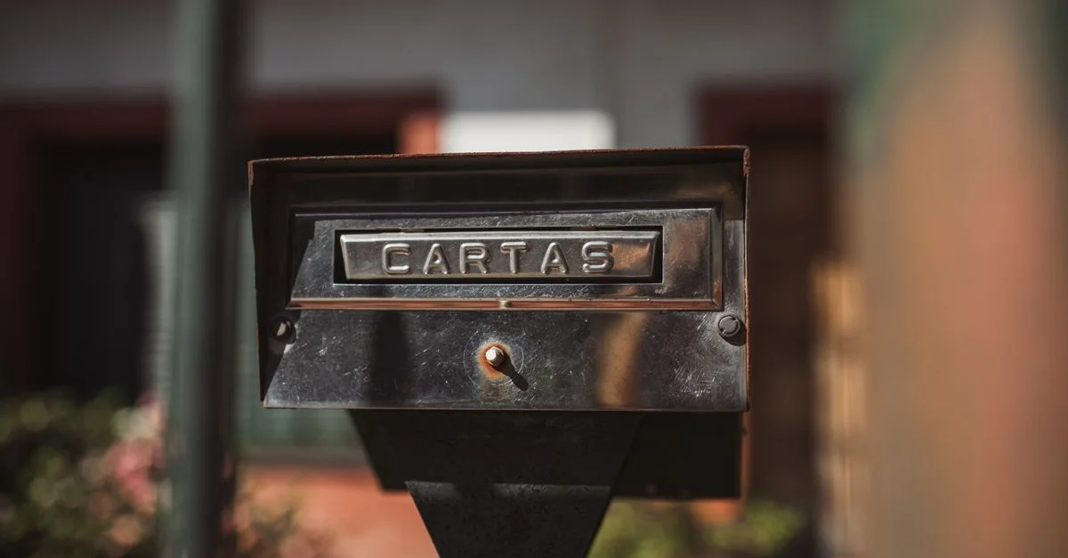 Gros plan d'une boîte aux lettres extérieure avec l'étiquette 'Cartas' dans un cadre ensoleillé.