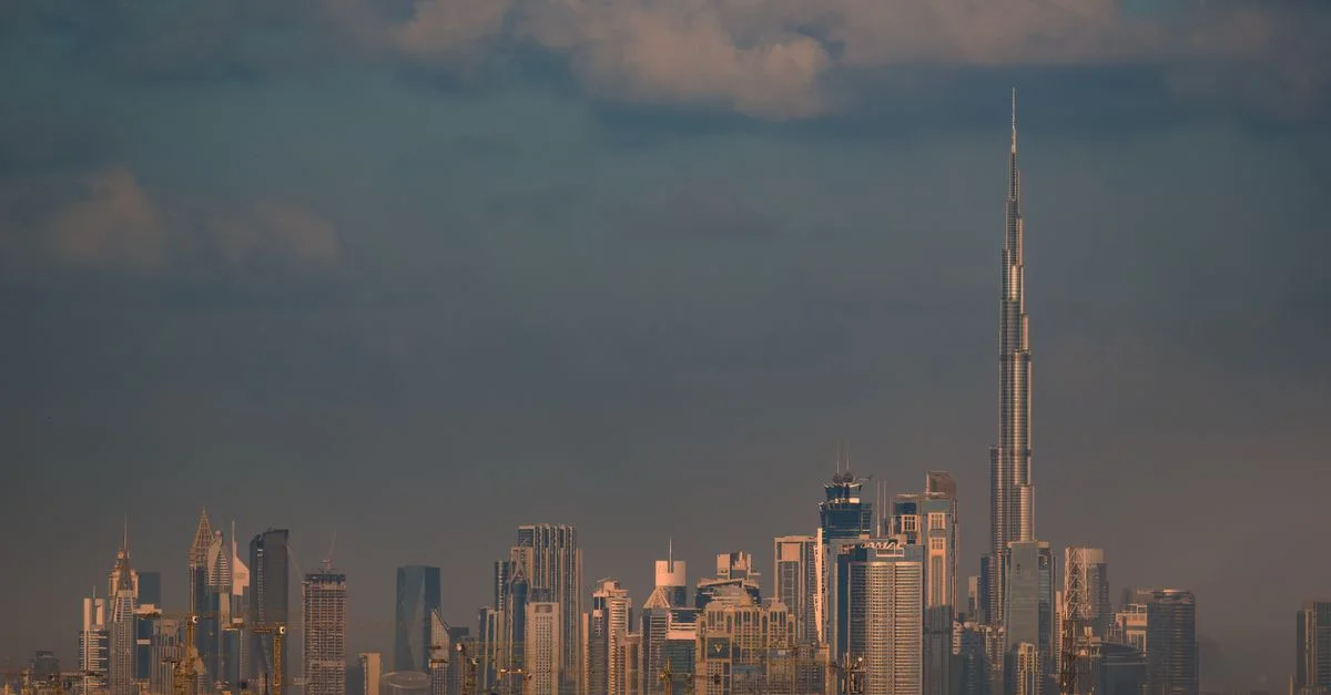 Vue époustouflante du skyline de Dubaï mettant en avant le célèbre Burj Khalifa au crépuscule sous un ciel nuageux.