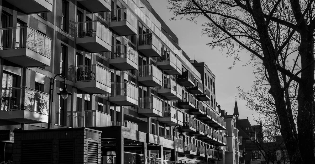 Photo en noir et blanc d'appartements modernes avec balcons dans un cadre urbain.