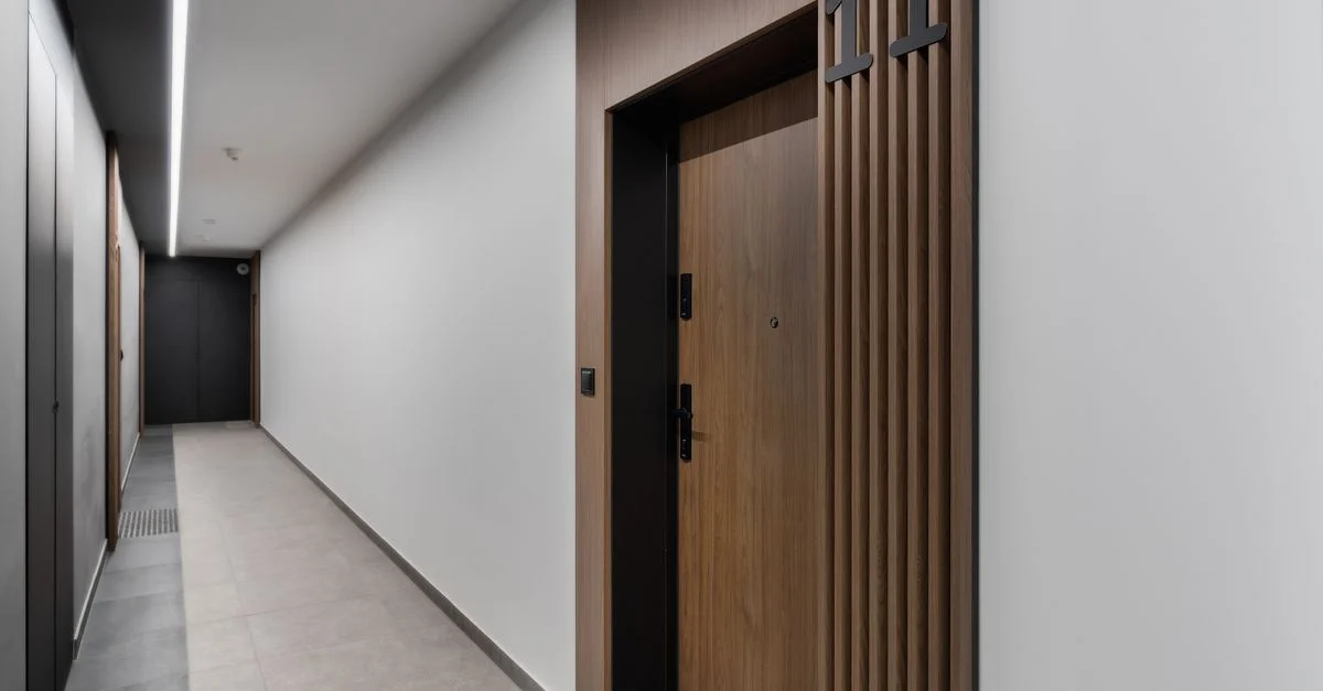 Couloir d'appartement élégant et moderne avec une porte en bois donnant sur la chambre numéro 11, dans un design minimaliste.