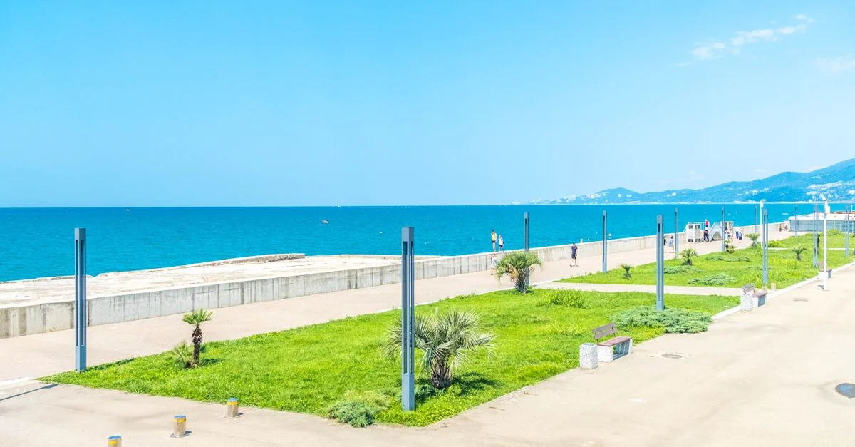 Vue lumineuse et ensoleillée de la promenade de Sochi au bord de la mer Noire avec un ciel bleu clair.