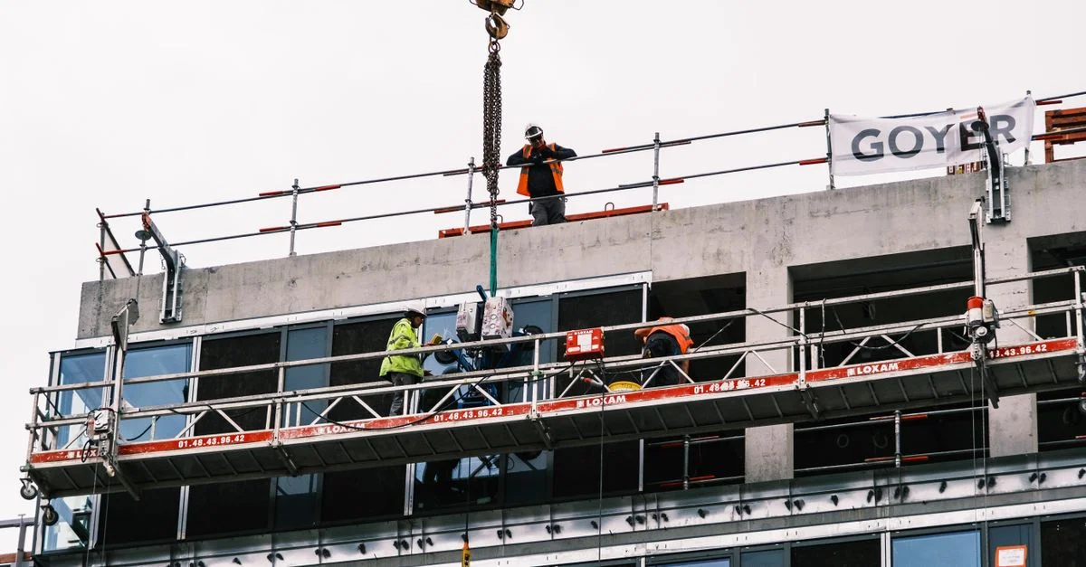Travailleurs professionnels sur un chantier gérant de l'équipement sur un immeuble de grande hauteur.