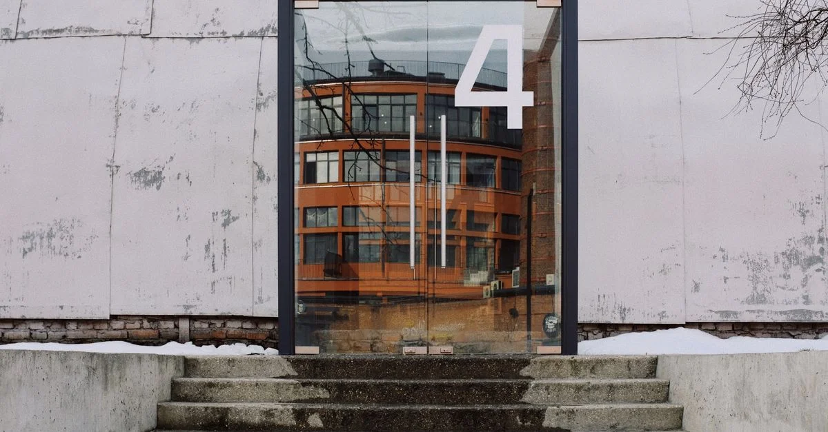 Porte en verre avec le numéro quatre reflétant l'architecture urbaine