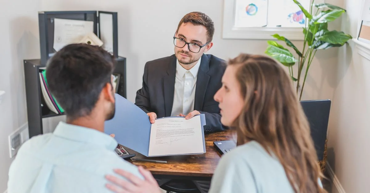 Consultation d'affaires avec des clients et un agent discutant d'un contrat à l'intérieur.