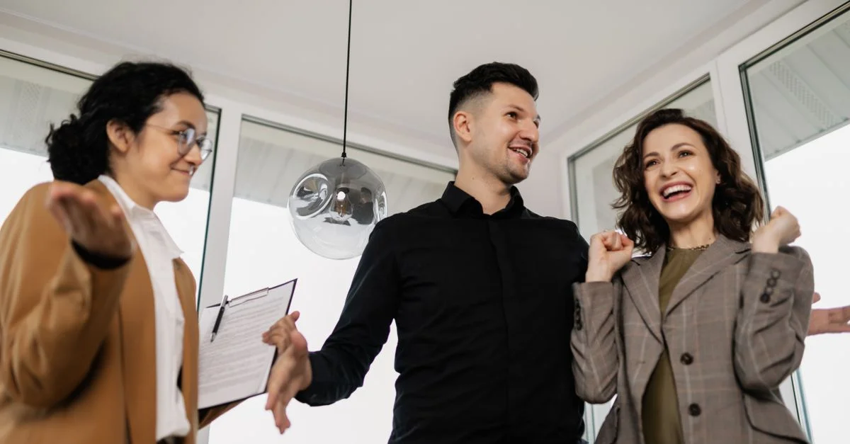 Un couple joyeux et leur agent immobilier célèbrent l'achat réussi de leur nouvelle maison à l'intérieur.